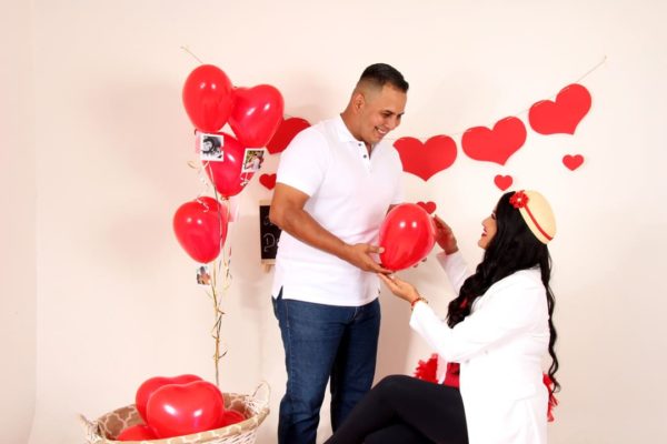 Pareja rodeada de globos rojos en forma de corazón