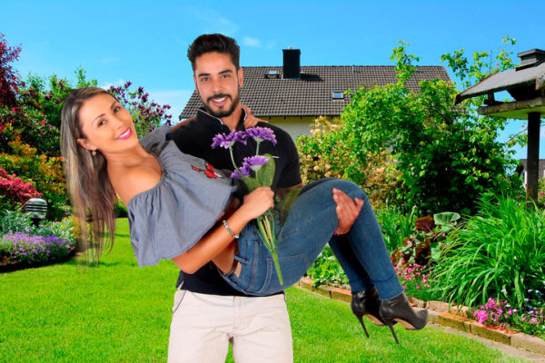 muchacho sostiene en brazos a su novia que sostiene un ramo de flores